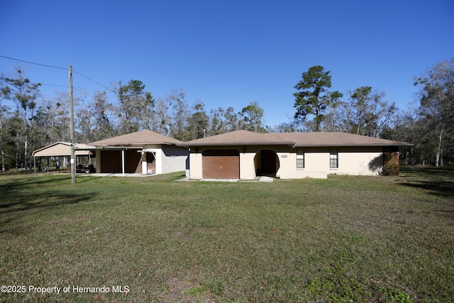 rear view of property with a carport, a lawn, an attached garage, and stucco siding