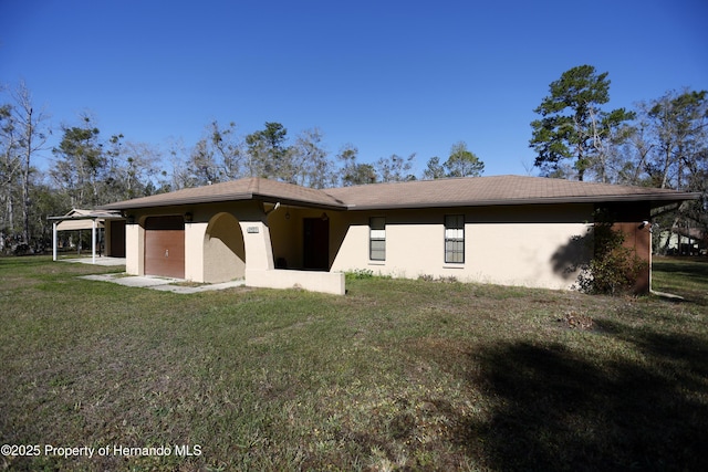 rear view of property featuring a lawn and stucco siding