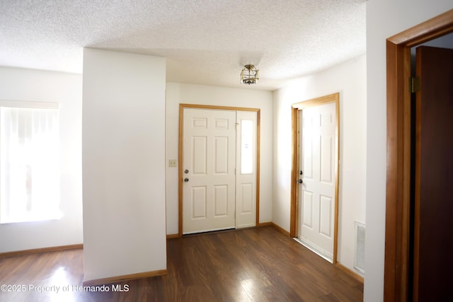 entryway featuring visible vents, baseboards, dark wood finished floors, and a textured ceiling