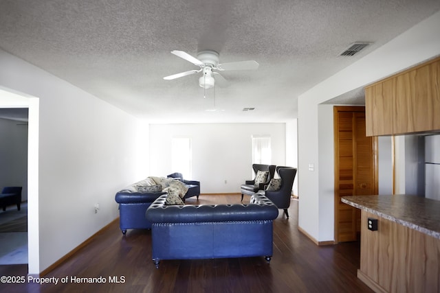 living area with dark wood finished floors, visible vents, a ceiling fan, a textured ceiling, and baseboards