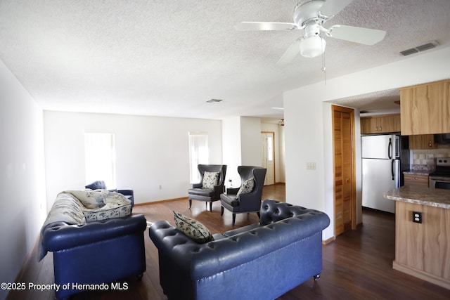 living room featuring dark wood-style floors, visible vents, and a textured ceiling