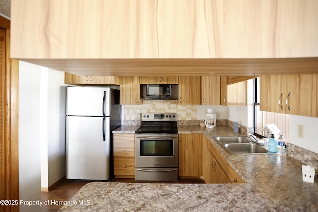 kitchen with black microwave, a sink, freestanding refrigerator, light stone countertops, and stainless steel electric range oven