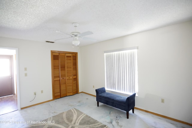 sitting room featuring light colored carpet, visible vents, a ceiling fan, a textured ceiling, and baseboards