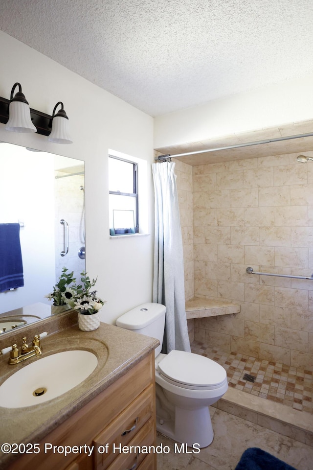 bathroom featuring toilet, a stall shower, vanity, a textured ceiling, and tile patterned flooring