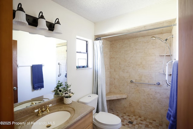 bathroom featuring toilet, a tile shower, a textured ceiling, and vanity