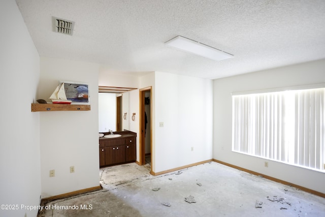 unfurnished bedroom with a sink, baseboards, visible vents, and a textured ceiling