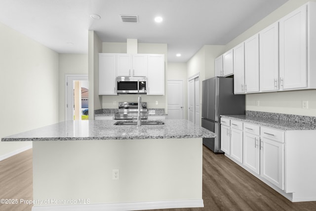 kitchen featuring a sink, visible vents, white cabinetry, appliances with stainless steel finishes, and an island with sink