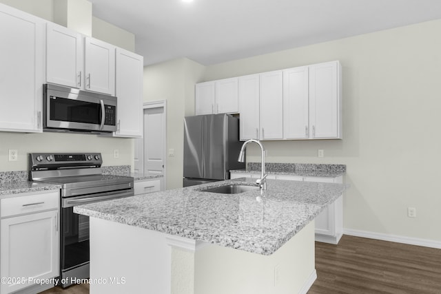 kitchen with stainless steel appliances, white cabinetry, a sink, an island with sink, and light stone countertops