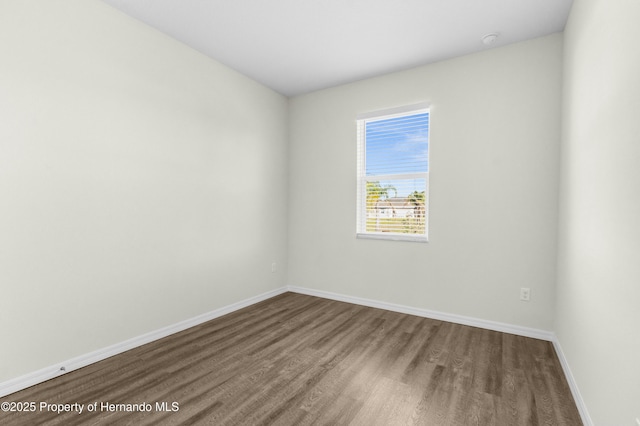 unfurnished room with baseboards and wood finished floors