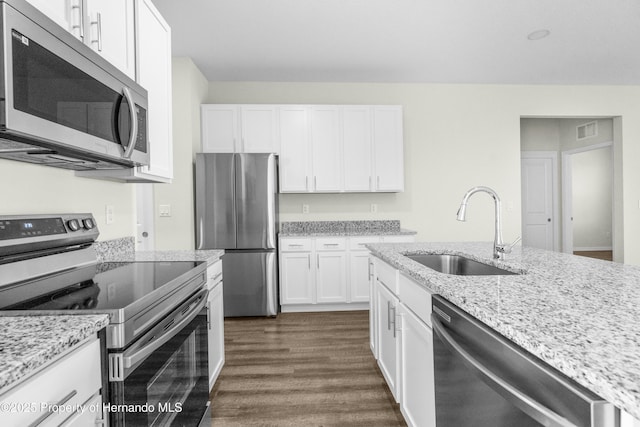 kitchen featuring white cabinets, light stone countertops, stainless steel appliances, and a sink