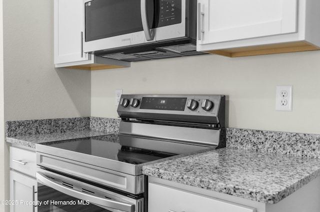 kitchen featuring white cabinets, light stone counters, and stainless steel appliances