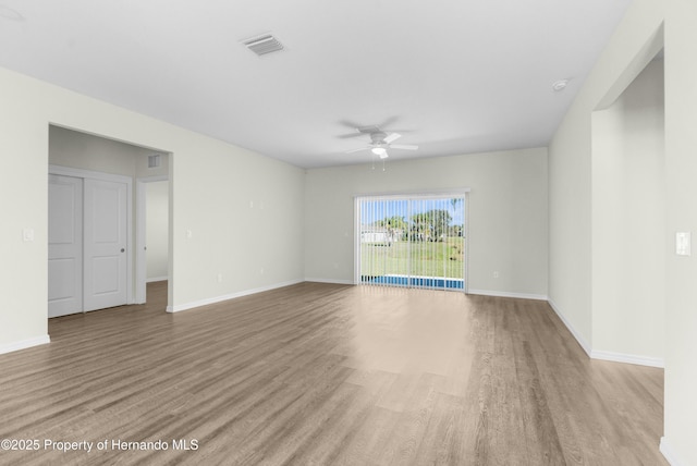 empty room with baseboards, light wood-type flooring, visible vents, and a ceiling fan