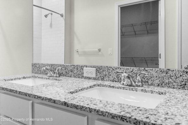 full bath featuring a sink, a spacious closet, and double vanity