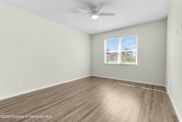 spare room featuring ceiling fan, baseboards, and wood finished floors