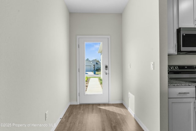 doorway to outside with baseboards and light wood-style floors