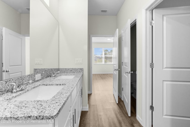 bathroom featuring double vanity, visible vents, a sink, and wood finished floors