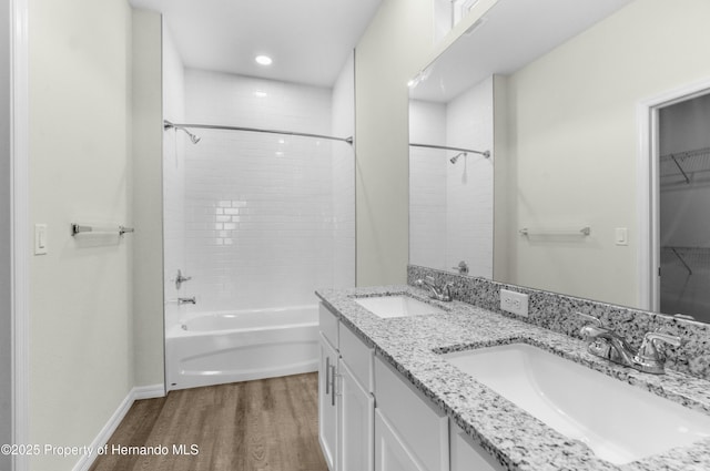 full bath with double vanity, a sink, bathing tub / shower combination, and wood finished floors