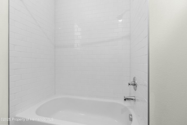 full bathroom featuring  shower combination and a textured wall