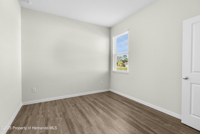 spare room with baseboards and wood finished floors