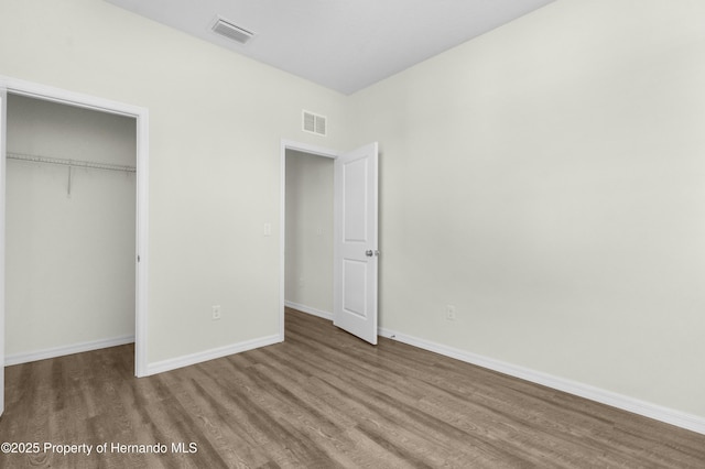 unfurnished bedroom with visible vents, baseboards, and wood finished floors