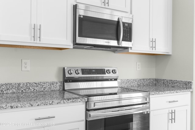 kitchen with appliances with stainless steel finishes, white cabinetry, and light stone countertops