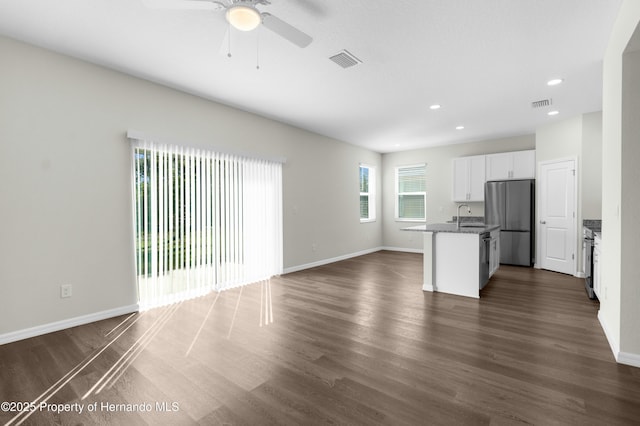 unfurnished living room with baseboards, visible vents, dark wood finished floors, and a sink