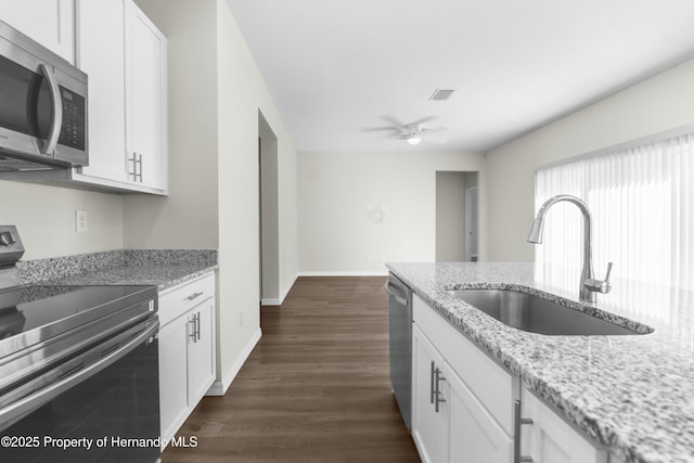 kitchen with light stone counters, a sink, visible vents, white cabinetry, and appliances with stainless steel finishes