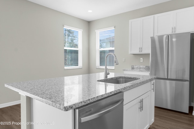 kitchen with appliances with stainless steel finishes, white cabinetry, a sink, and a center island with sink