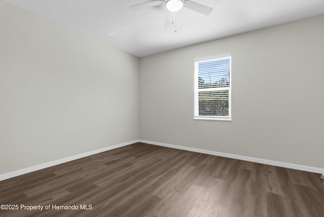 empty room with dark wood-style floors, ceiling fan, and baseboards