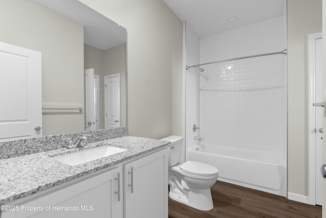 bathroom with toilet, washtub / shower combination, wood finished floors, and vanity