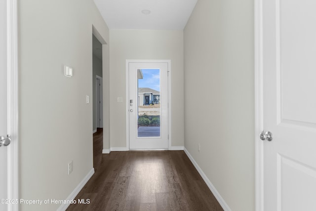 doorway featuring dark wood-type flooring and baseboards