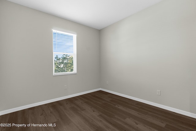 spare room with dark wood-style floors and baseboards