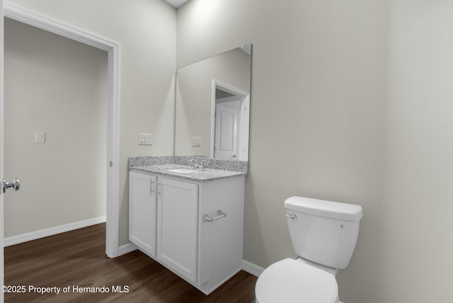 bathroom with toilet, wood finished floors, vanity, and baseboards