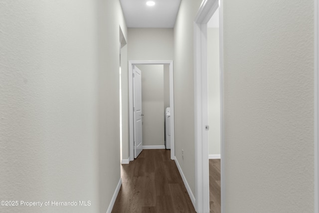 corridor featuring washer / dryer, baseboards, and dark wood-style flooring