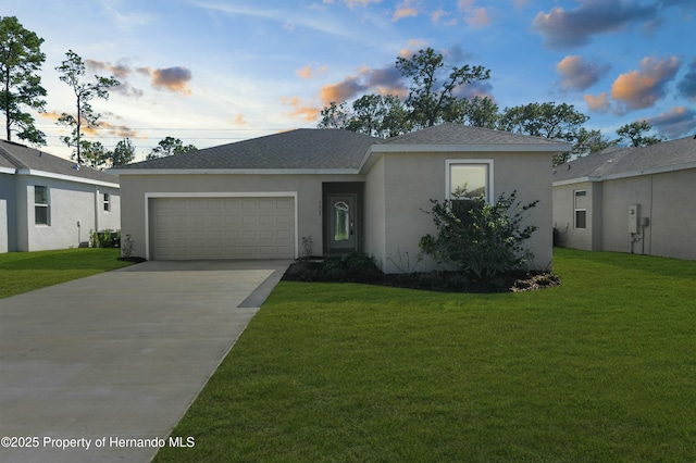 ranch-style home featuring a garage, driveway, a shingled roof, a yard, and stucco siding