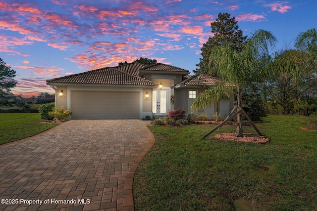 mediterranean / spanish house featuring a front lawn, decorative driveway, and an attached garage