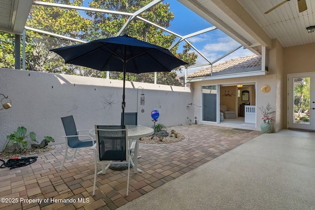 view of patio featuring a lanai, fence, and outdoor dining space