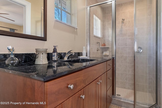 bathroom featuring a stall shower, a textured wall, and vanity