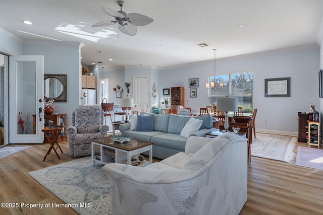 living room with light wood-style flooring, baseboards, and crown molding