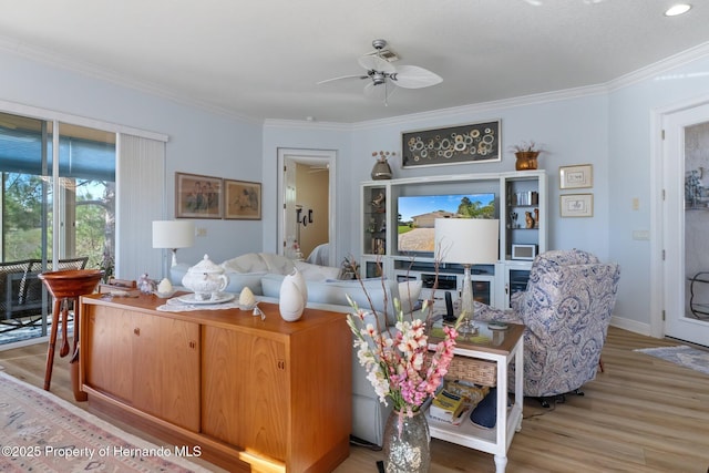 living room with light wood finished floors, baseboards, ornamental molding, and a ceiling fan