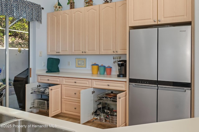 kitchen with light brown cabinetry, light countertops, and freestanding refrigerator