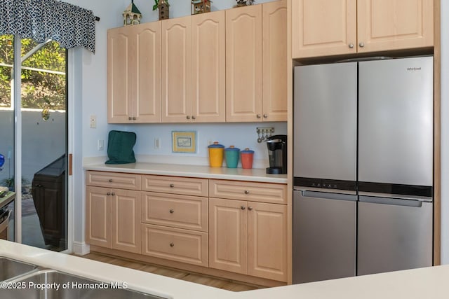 kitchen featuring light brown cabinetry, light countertops, and freestanding refrigerator