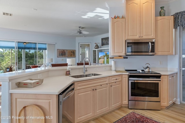 kitchen featuring appliances with stainless steel finishes, visible vents, a sink, and light brown cabinets