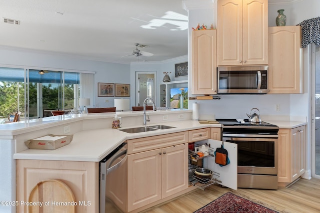 kitchen with visible vents, ornamental molding, stainless steel appliances, light brown cabinetry, and a sink