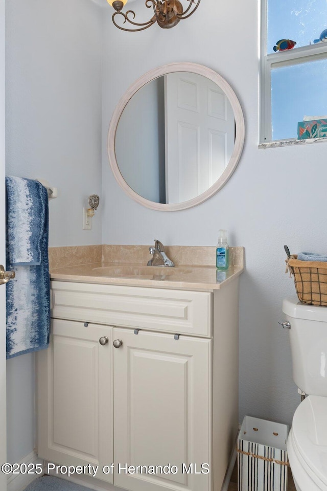 half bath featuring vanity and toilet