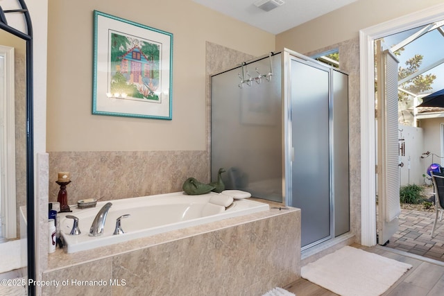 bathroom with a stall shower and a garden tub