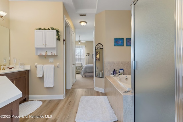 bathroom featuring a garden tub, visible vents, vanity, ensuite bath, and wood finished floors