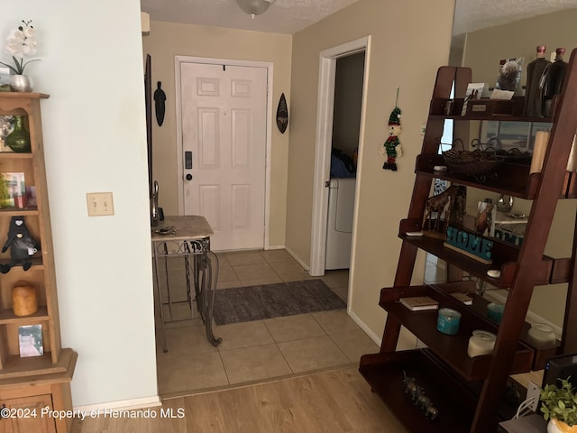 entryway featuring washer / dryer, baseboards, and light tile patterned floors