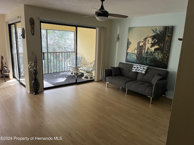 living area with a textured ceiling, ceiling fan, and wood finished floors