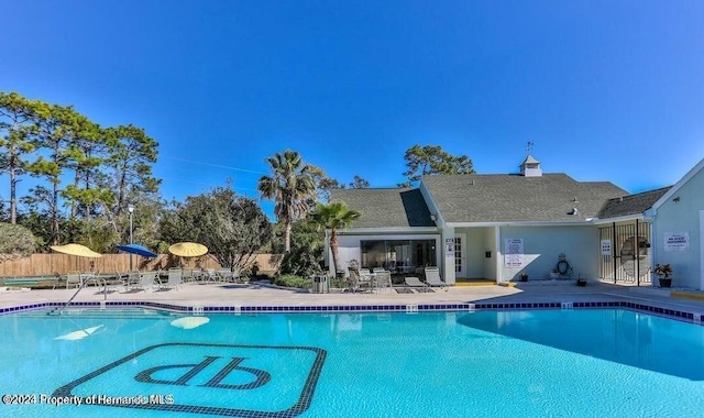 pool with a patio and fence